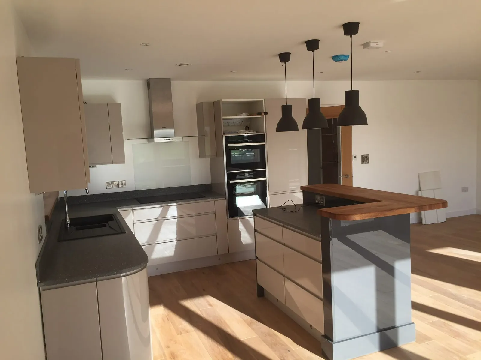 Gloss kitchen with oak breakfast bar – kitchen fitting by JCK Carpentry & Building, Exeter